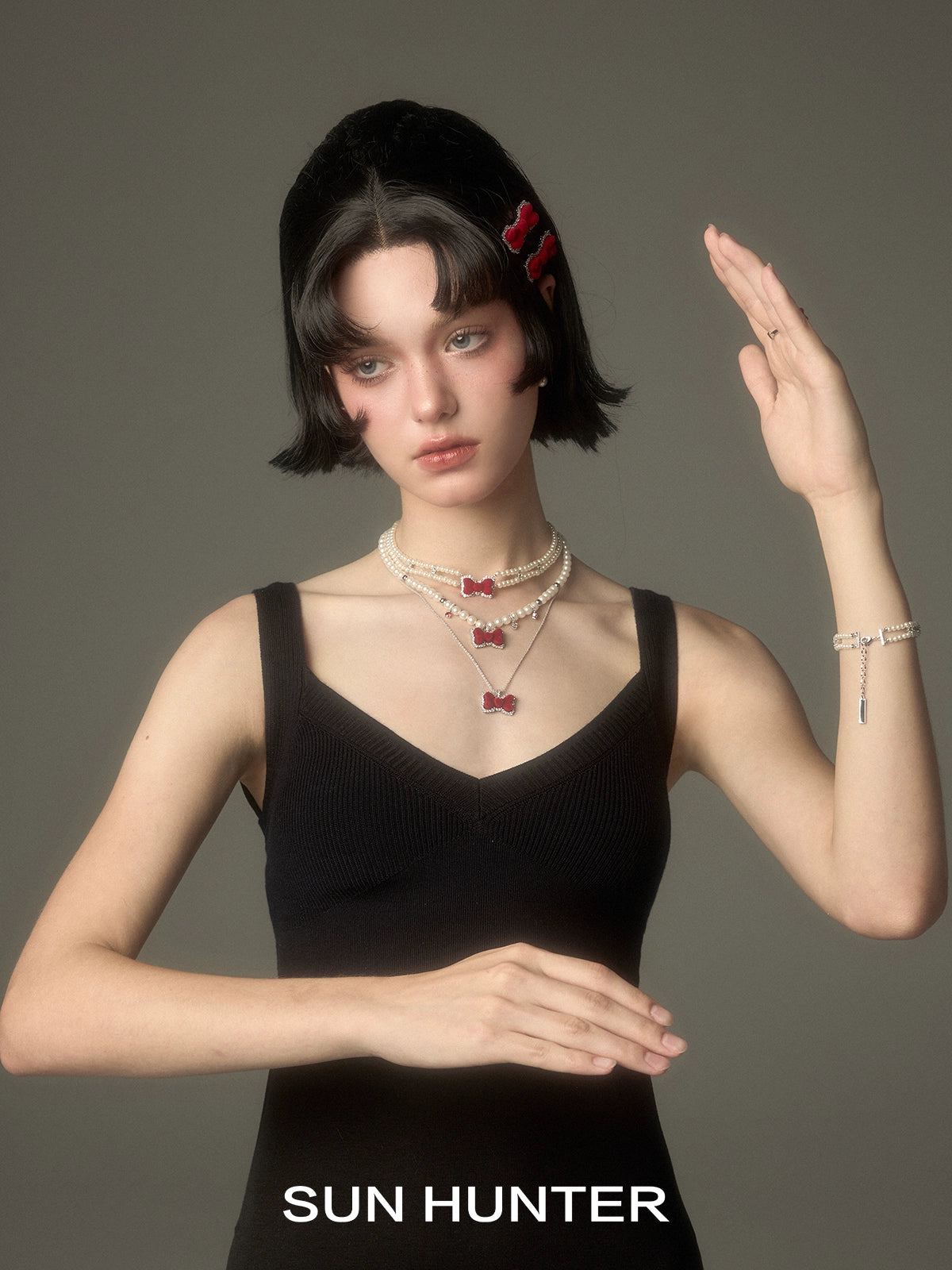 Model wearing a SUN HUNTER velvet bow pearl bracelet along with layered necklaces and stylish attire