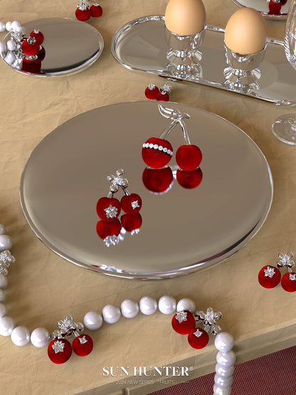 Elegant velvet cherry pearl ring showcased on a reflective plate with decorative cherries and pearls