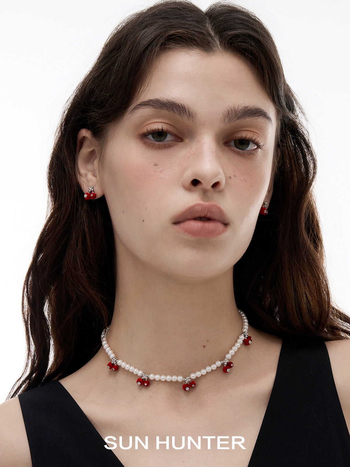 Model wearing SUN HUNTER velvet cherry stud earrings with a matching necklace and a simple black dress