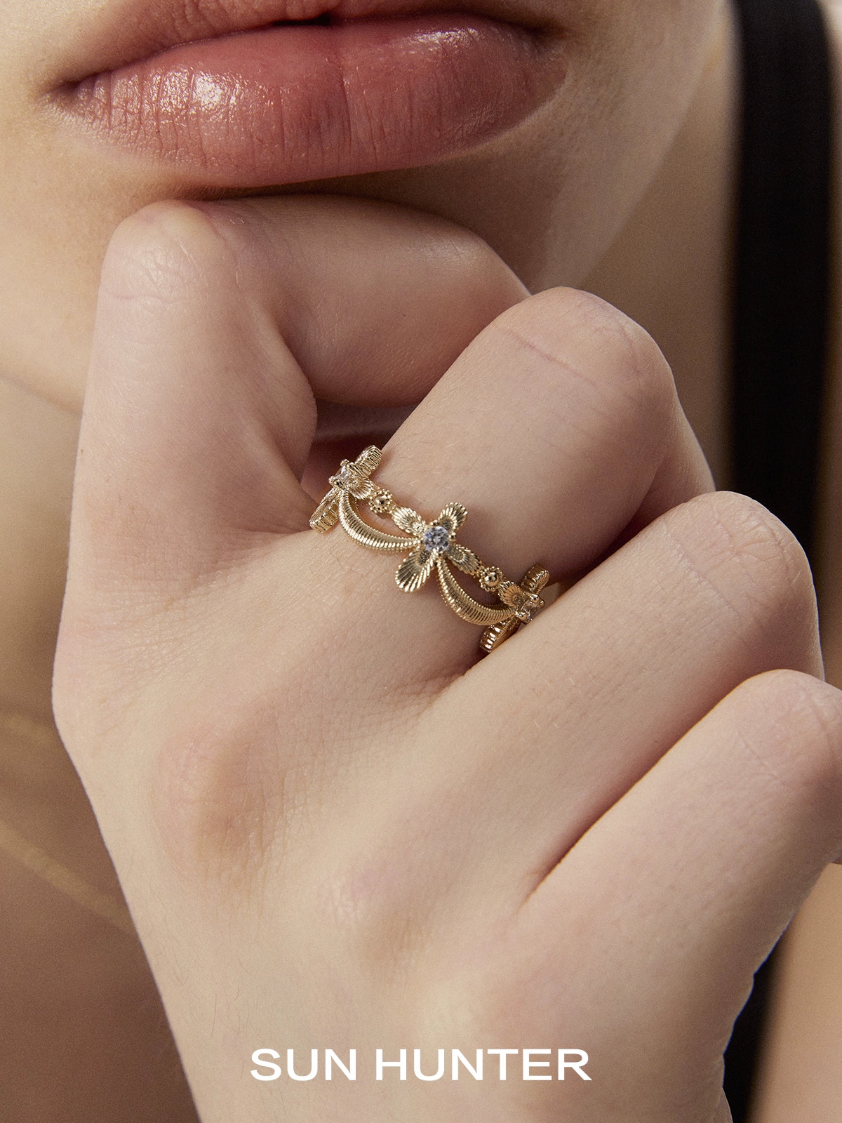 Elegant SUN HUNTER shimmer cross ring with intricate design worn on a model's finger