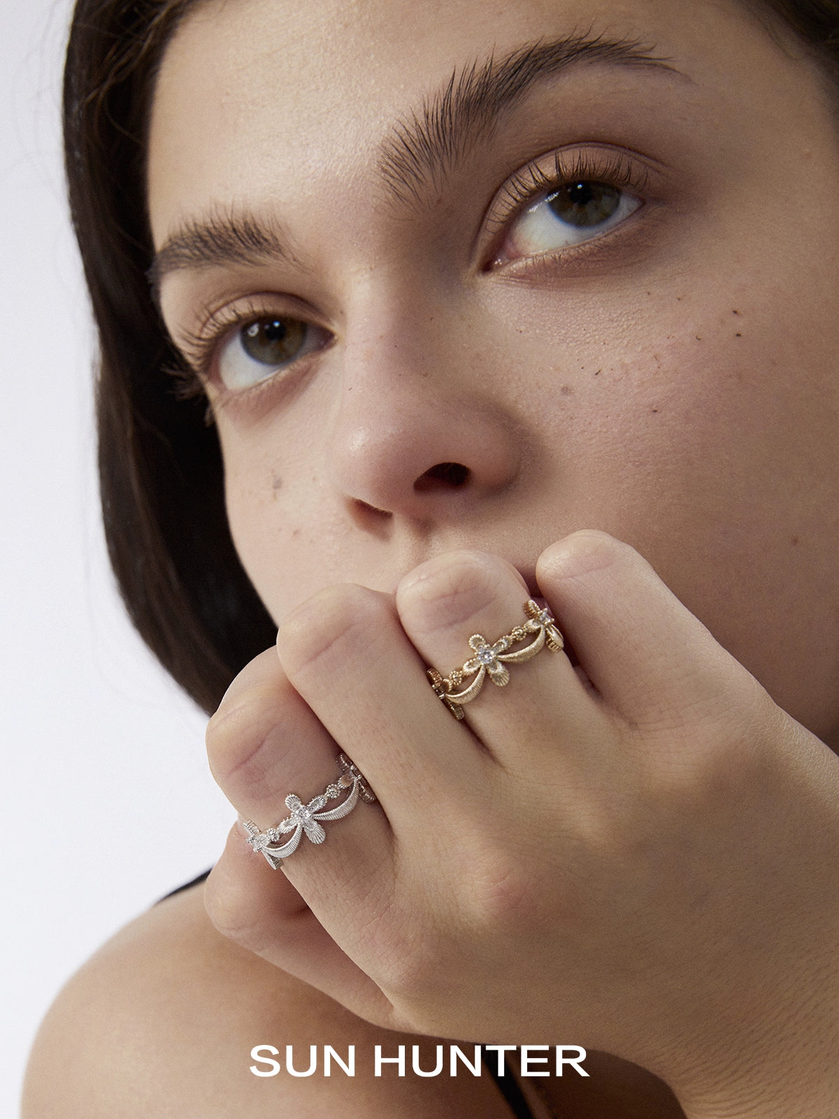 Model wearing two SUN HUNTER shimmer cross rings in silver and gold showcasing elegant design