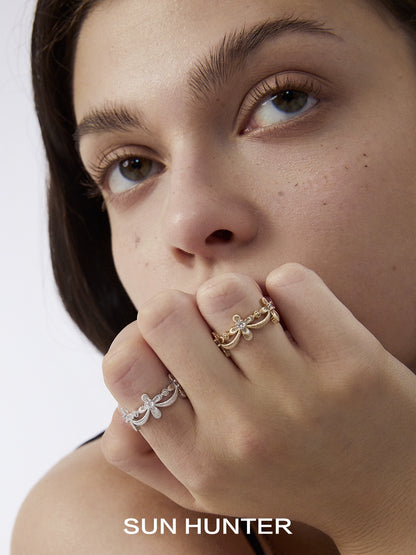Model wearing two SUN HUNTER shimmer cross rings in silver and gold showcasing elegant design