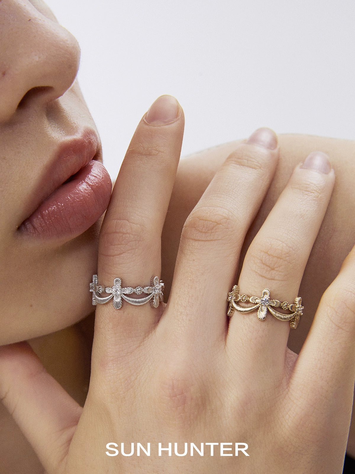 Elegant SUN HUNTER shimmer cross ring in silver and gold on a model's fingers