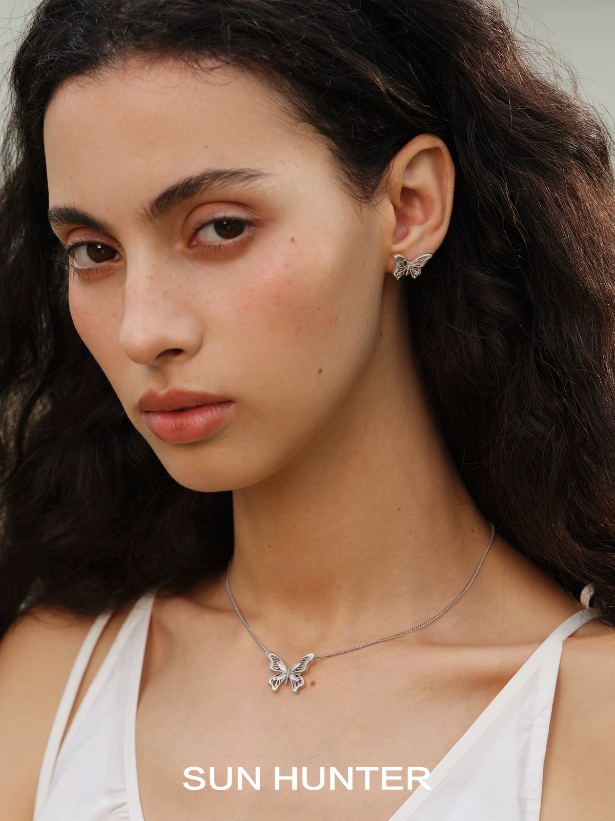 SUN HUNTER vintage butterfly earrings in silver, elegantly worn by a model with natural makeup