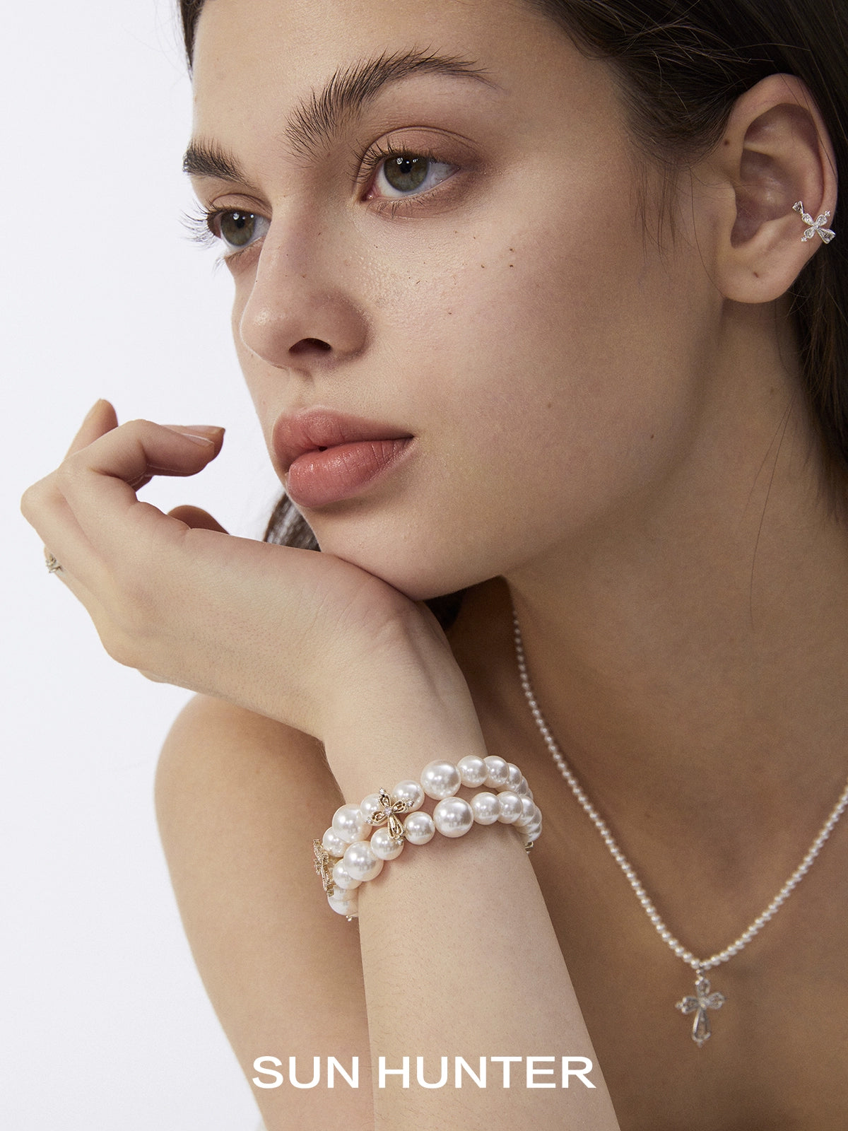 SUN HUNTER vintage cross pearl bracelet elegantly worn on a model's wrist with young adult styling