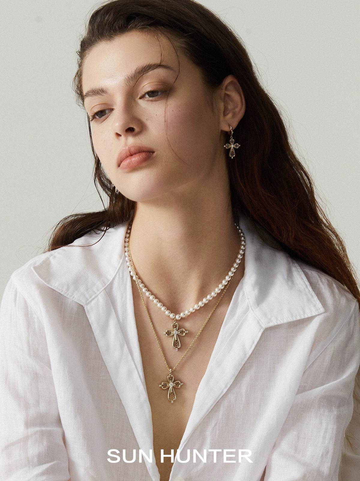 Model wearing a SUN HUNTER vintage cross pearl necklace with elegant design and matching earrings