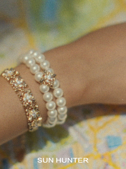 SUN HUNTER vintage iris pearl bracelet paired with a sparkling gold bracelet on a wrist