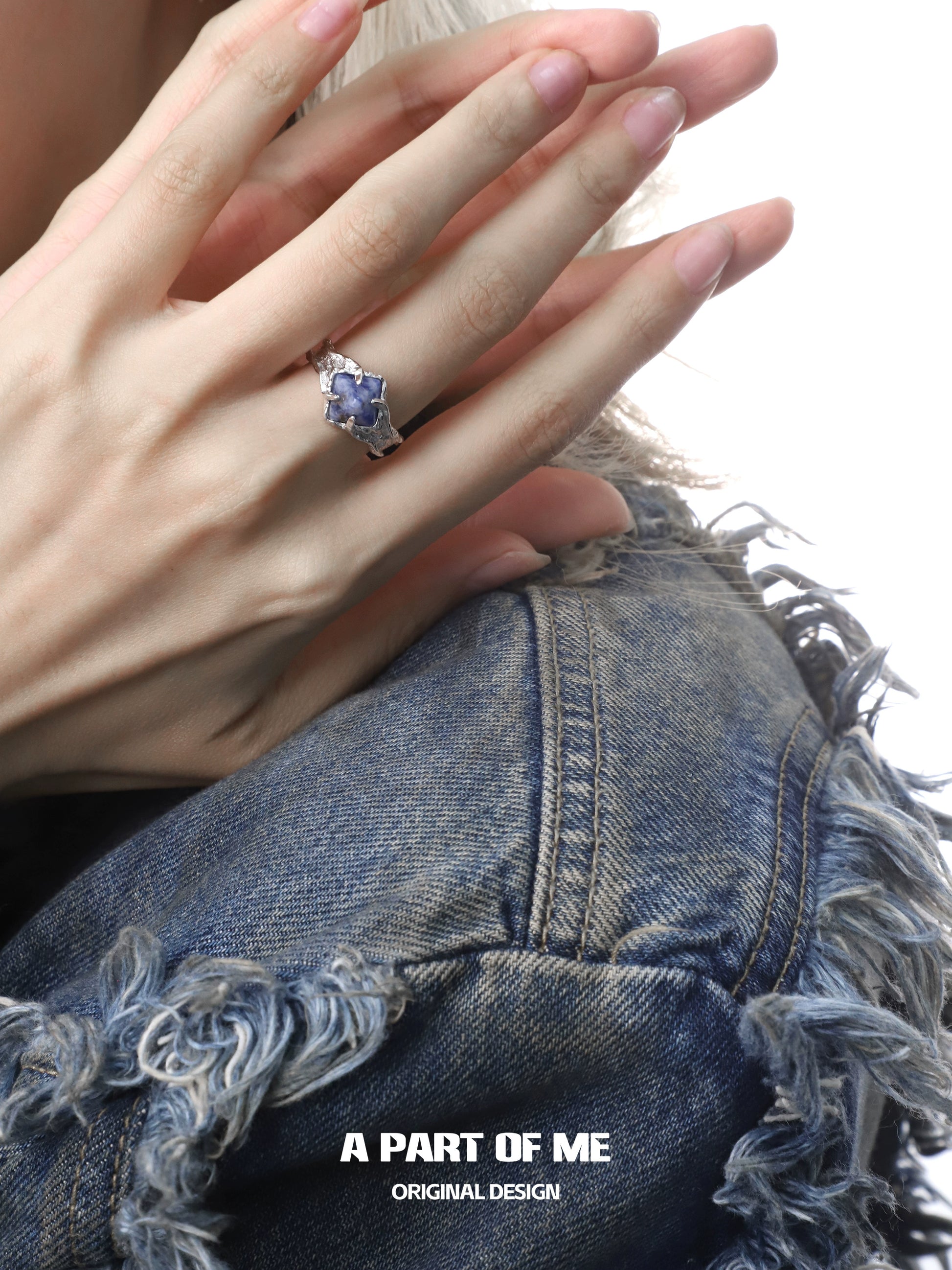 Elegant violet gemstone ring set in silver worn on a hand with a stylish denim jacket