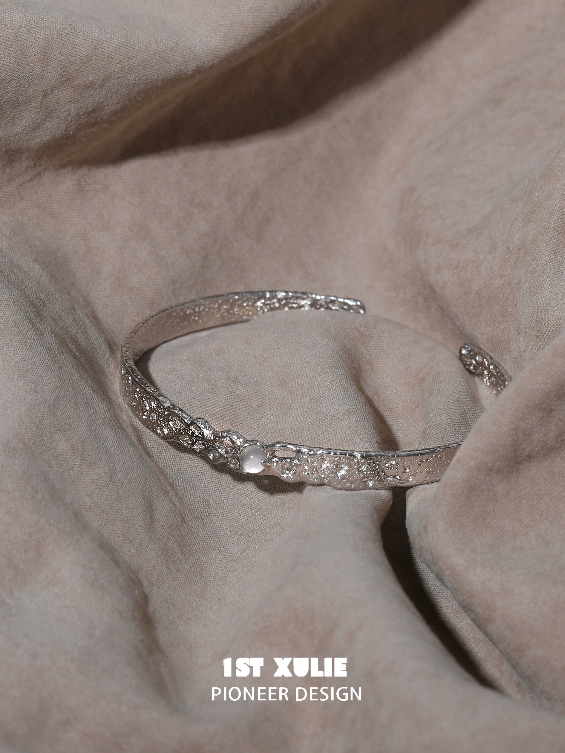 Elegant white agate bangle bracelet on a soft fabric background, showcasing intricate details