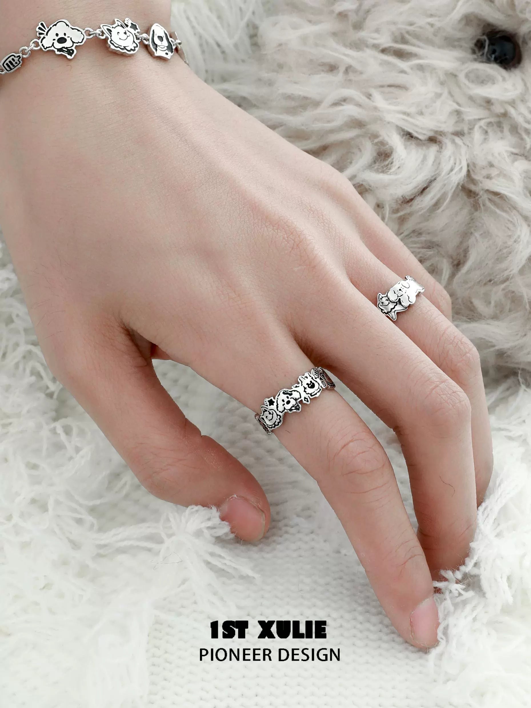 Hand wearing a cute Y2K puppy silver ring alongside a matching bracelet on a fluffy background